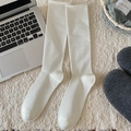 White ribbed cotton blend knee-high socks displayed in a cozy home setting - Cream