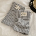 Light gray cable knit leg warmers with vintage label on soft white linen bedding - One Size / Light Gray