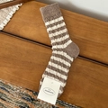 Gestreifte Wollsocken in Kaffee und Creme mit Zopfmuster auf dunklem Holzgrund - Khaki