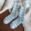 Blau-weiß gestreifte Wollstricksocken mit kleinem Etikett auf gemütlichem Hintergrund - Graublaue Streifen
