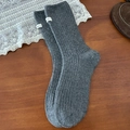 Calze spesse in lana grigio scuro con etichetta bianca su sfondo in legno scuro - Taglia unica / Grigio Medio