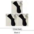 Three pairs of black mid-calf cotton crew socks in a minimalist aesthetic flat lay - All Black Style
