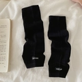 Scaldamuscoli in maglia a coste nere con etichetta minimalista su sfondo di stoffa bianca - Taglia unica / Nero