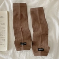 Scaldamuscoli marroni a coste con etichetta del marchio in uno stile flat lay accogliente - Taglia unica / caffè