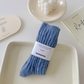 Blue cable knit crew socks in plush fabric with white paper packaging band - One Size / Denim Blue