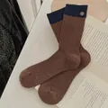 Calze a coste marroni e blu navy con dettagli di bottoni in metallo retrò su libro bianco - Caramello