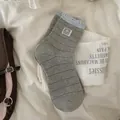 Dark gray striped crew socks with light blue lace trim and panda patch on fabric - One Size / Light Gray