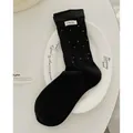 Chaussettes mi-hautes en coton noir à pois blancs avec étiquette sur une assiette blanche - Noir