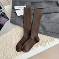 Dark brown wool knit calf socks with vertical texture and rolled edges on soft rug - Brown