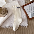 Cremeweiße Rippstricksocken mit blauem Sustainable-Etikett am Knöchelbündchen - Cremeweiß