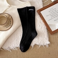 Schwarze gerippte Socken mit nachhaltigem Lederaufnäher auf gemütlichem Strickhintergrund - Schwarz