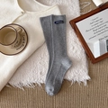 Graue gerippte Socken mit blauem nachhaltigem Label-Tag auf gemütlichem Hintergrund - Grau