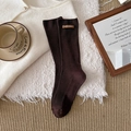Dark coffee brown ribbed mid-calf socks with sustainable leather tag on cozy white rug - Dark Coffee