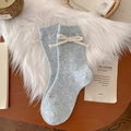 Light blue wool socks with colorful flecks and white bow tie detail in a cozy setting - One Size / Blue