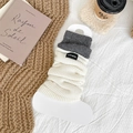 Jambières tricotées blanches avec bordure grise et étiquette Hand Made sur fond cosy - Blanc et Gris Contrasté