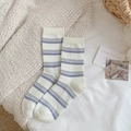 Chaussettes blanches à rayures bleues avec bords-côtes sur un lit blanc douillet - Rayé Blanc