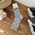 Grey crew socks with black bow patterns and ruffled cuffs on wooden background - Light Grey Small Bow