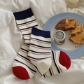 Navy blue striped cotton crew socks with red heel and toe in a cozy home setting - Thin Stripes