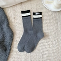 Calze grigio scuro con strisce varsity ed etichetta tessuta in una posa piatta accogliente - grigio scuro