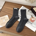 Dark grey cable-knit mid-calf socks with egg label in a lifestyle wooden tray setting - One Size / Dark Gray