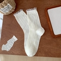 White crew socks with lace trim and bow patterns laid on a rustic wooden background - Lace Trim