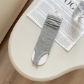 Grey ribbed knit leg warmers with stirrup design and fashion brand tag on white desk - Light Gray