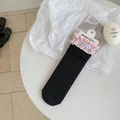 Calze a coste nere con bordo a balze a quadretti rosa ed etichetta del marchio su tavolo - Bordo Rosa Nero