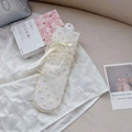 Beige sheer tulle socks with mesh dots and elegant ribbon bow detail displayed on fabric - Yellow