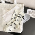 Beige crew socks with black heart pattern and satin bow accent in balletcore style - White