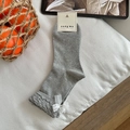 Grey crew socks featuring white lace bow accents and branded tag in a cozy lifestyle setting - One Size / Grey