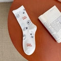 Cute white crew socks featuring cartoon sheep and Cool Sheep text on a wooden table - Bow Sheep