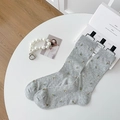 Calze grigie con ricami floreali su tavolo bianco con eleganti accessori di perle - Grigio