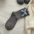 Calzino lavorato a maglia grigio scuro con fiocco azzurro su superficie trapuntata bianca - Taglia unica / grigio scuro