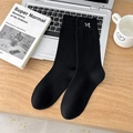 Black ribbed mid-calf cotton socks featuring white bow embroidery on a minimalist desk - Black
