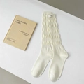 Calcetines amontonados blanco crema con textura de burbujas y pequeña etiqueta de letras - Talla única / crema