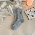 Grey wool blend crew socks featuring black embroidered bow detail in a cozy home setting - Gray