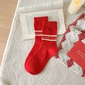 Red cotton crew socks with white stripes and smiley face embroidery displayed on a rug - One Size / Small Smiley Pattern