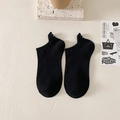 Black cotton low cut socks with eye embroidery on heel over a minimalist background - Solid Black