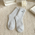 Light grey fluffy coral fleece socks with black bow embroidery on textured carpet - One Size / Blue Gray