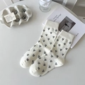 Mid-calf cream socks featuring black heart patterns and bow details in a flat lay view - Heart Pattern / White