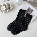 Fashionable black crew socks featuring white bow patterns on a minimalist tabletop - White Bow Pattern / Black