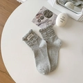Gray ruffled knit socks with frilled edges and brand tag on a clean lifestyle setting - One Size / Gray