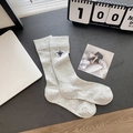 Light gray ribbed mid-calf socks with blue embroidered logo on deep wood background - Grey Bee (Crew)