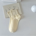 Solid cream white cotton mid-calf socks with ribbed cuffs on a minimalist book background - Yellow