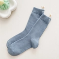 Solid light blue mid-calf ribbed socks with a yellow smiley face fabric label - Blue