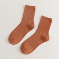 Solid caramel brown ribbed cotton crew socks in a cozy minimalist flat lay arrangement - Dirty Orange