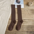 Chaussettes montantes en tricot marron foncé avec texture à côtes verticales sur bois - Marron
