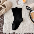 Thick black wool maternity socks for winter, soft knit texture on white plush rug - Black