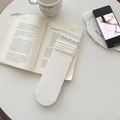 Weiße Socken im Ballett-Stil mit Spitzenborte und Rippenstruktur auf offenem Buch - Einheitsgröße / Salatrand-Stil