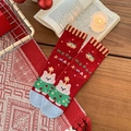 Calze natalizie in cotone rosso con motivo a orsetto e scritta Merry X-mas su tavolo - Taglia unica / Campana